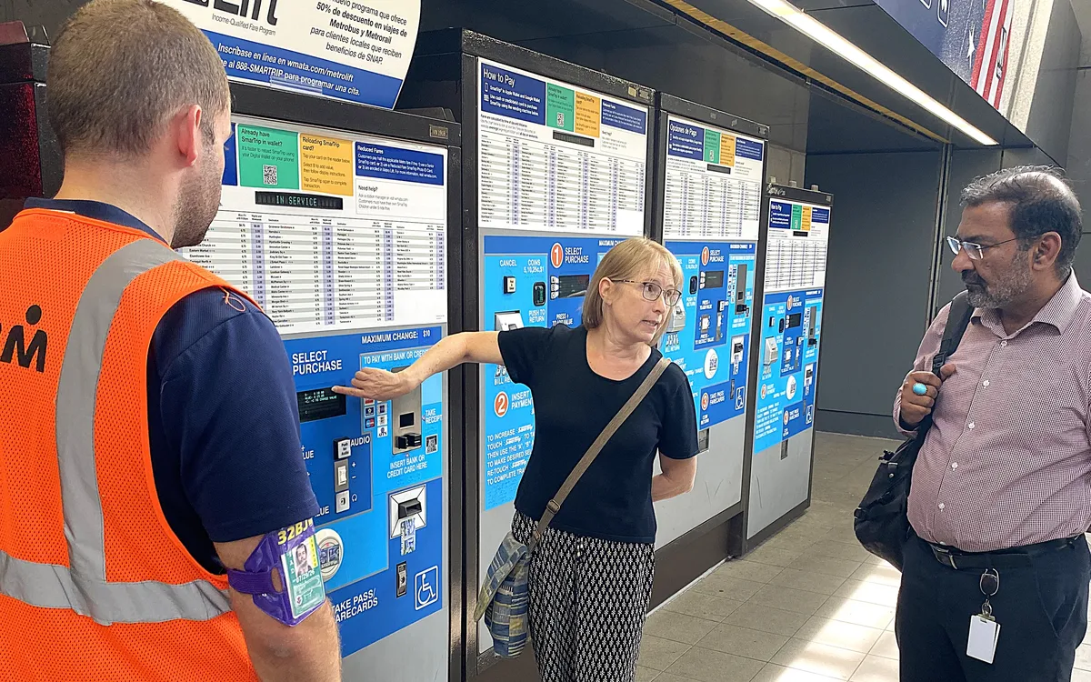 A DATA staff member showing two workers how to use a Metro fare machine.