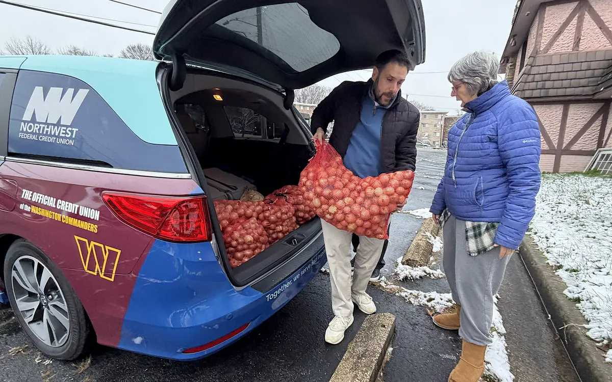 Volunteers unloading bags of produce from a van for food delivery.