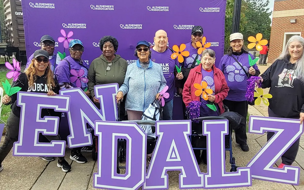 Older adults holding large END ALZ letters at an Alzheimer's Association walk.