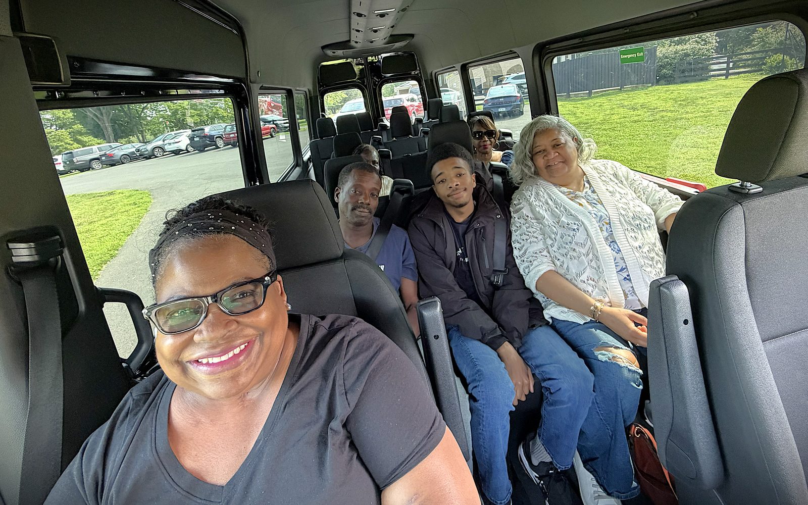 Five riders smile from their seats inside a Venture Out van.
