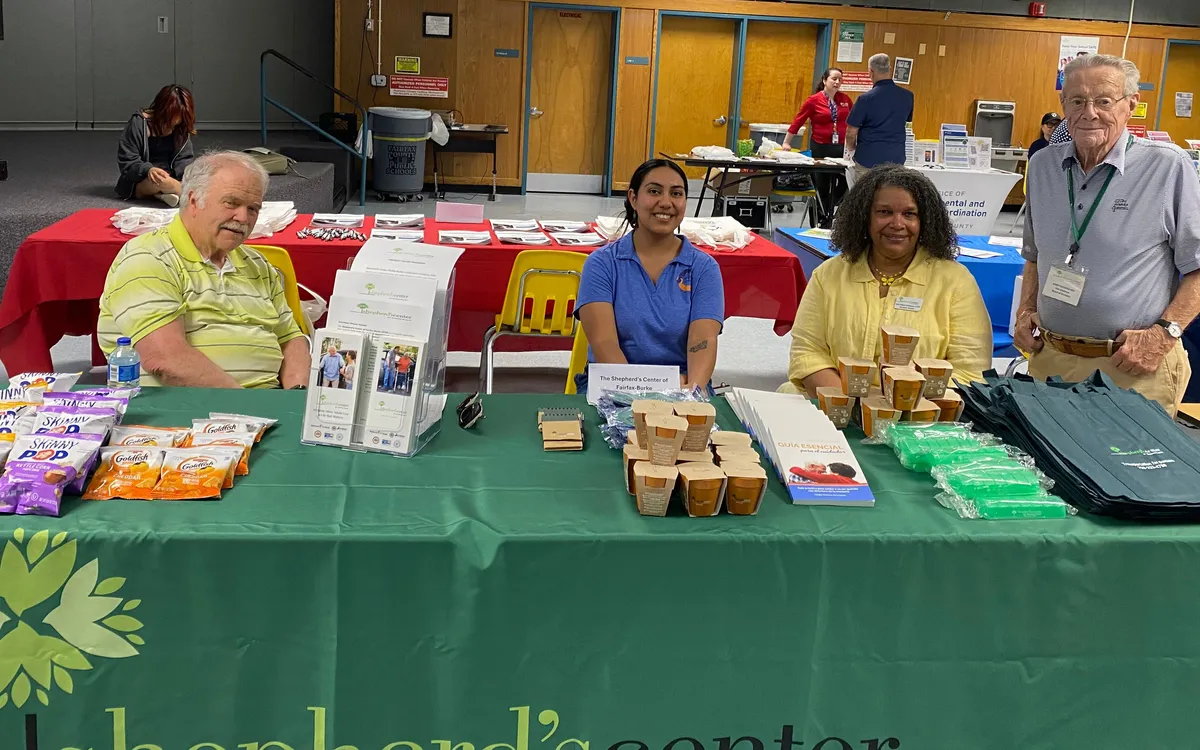 Four volunteers smiling behind a community outreach table.